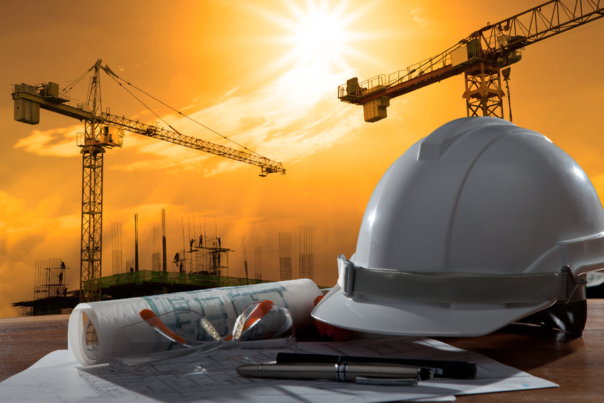 file of safety helmet and architect pland on wood table with sunset scene and building construction